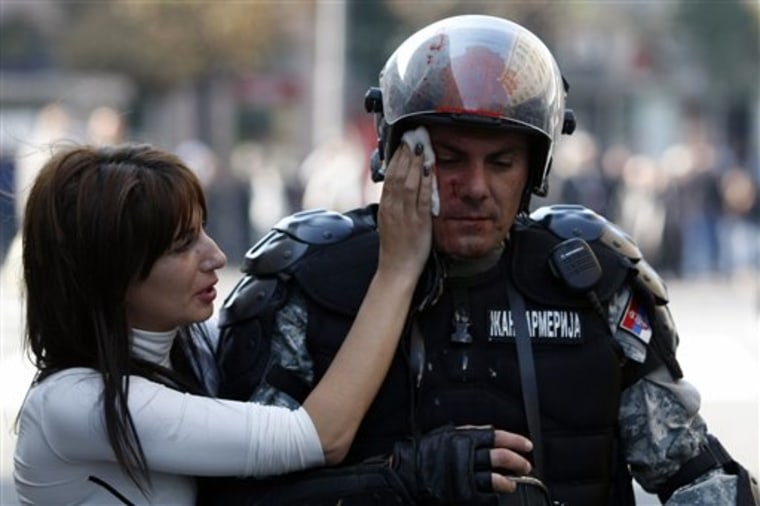 A member of the Serbian riot police is assisted by passer-by, during the anti-gay riots in Belgrade, Serbia, on Sunday. Riot police in Serbia clashed with hundreds of far-right supporters who tried to disrupt a gay pride march in downtown Belgrade. More than a dozen people were injured, officials said. 